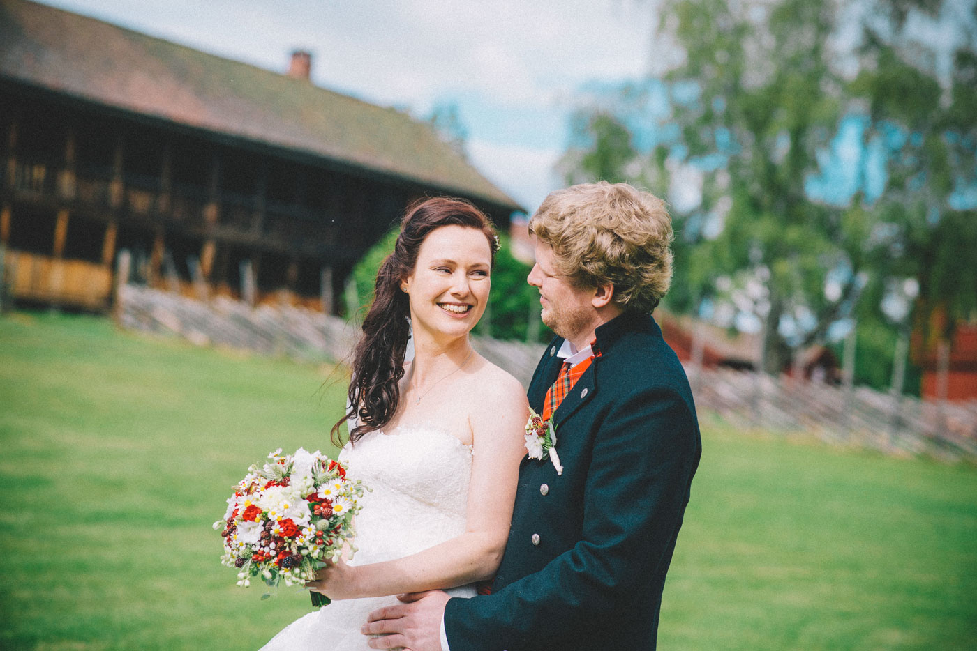 Bryllupsfotografering der brud smiler med blomster, brudgom holder henne